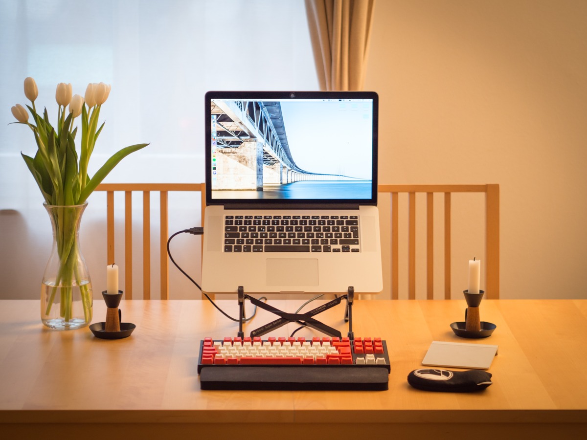  A computer sitting on a desk, a mechanical keyboard in front and two candles to each side. 