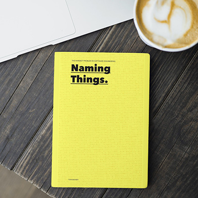  Naming things, a book with a bright yellow cover, on a dark table. Next to a coffee cup. 