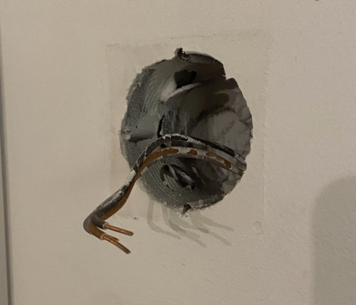 A hole in the wall, three cables are visible