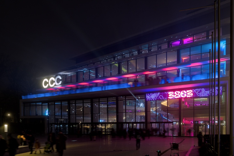  The entry of the conference hall where the 38c3 took place in Hamburg at night. The entry has a purple lid up sign that says 38c3. At the corner of the building you see 3 white glowing letters: CCC 